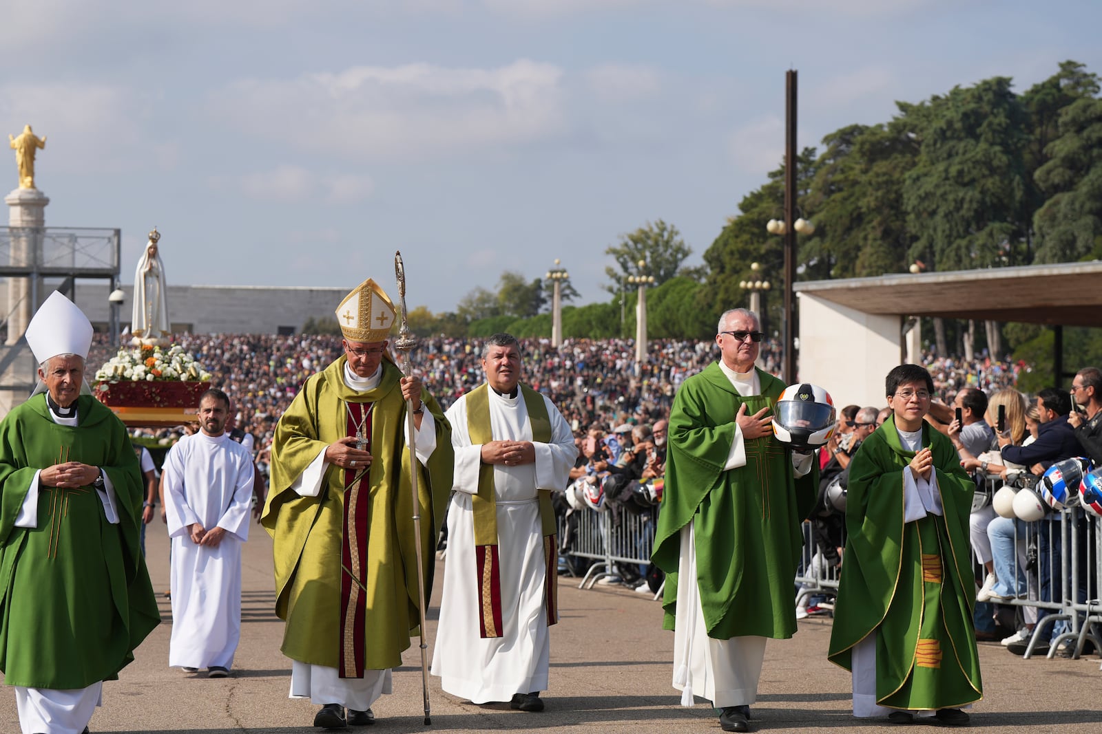 A priest carrying a Portuguese National Republican Guard motorcyclist helmet walks ahead of the Our Lady of Fatima statue in a procession starting the IX Pilgrimage of the Blessing of Helmets at the Roman Catholic holy shrine of Fatima to attend, in Fatima, Portugal, Sunday, Sept. 22, 2024. (AP Photo/Ana Brigida)