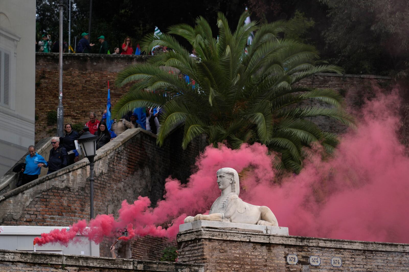 Workers of automotive sector burn flares as they arrive in Rome's Piazza Del Popolo Square during a demonstration on the occasion of their national strike, Friday, Oct. 18, 2024. (AP Photo/Gregorio Borgia)