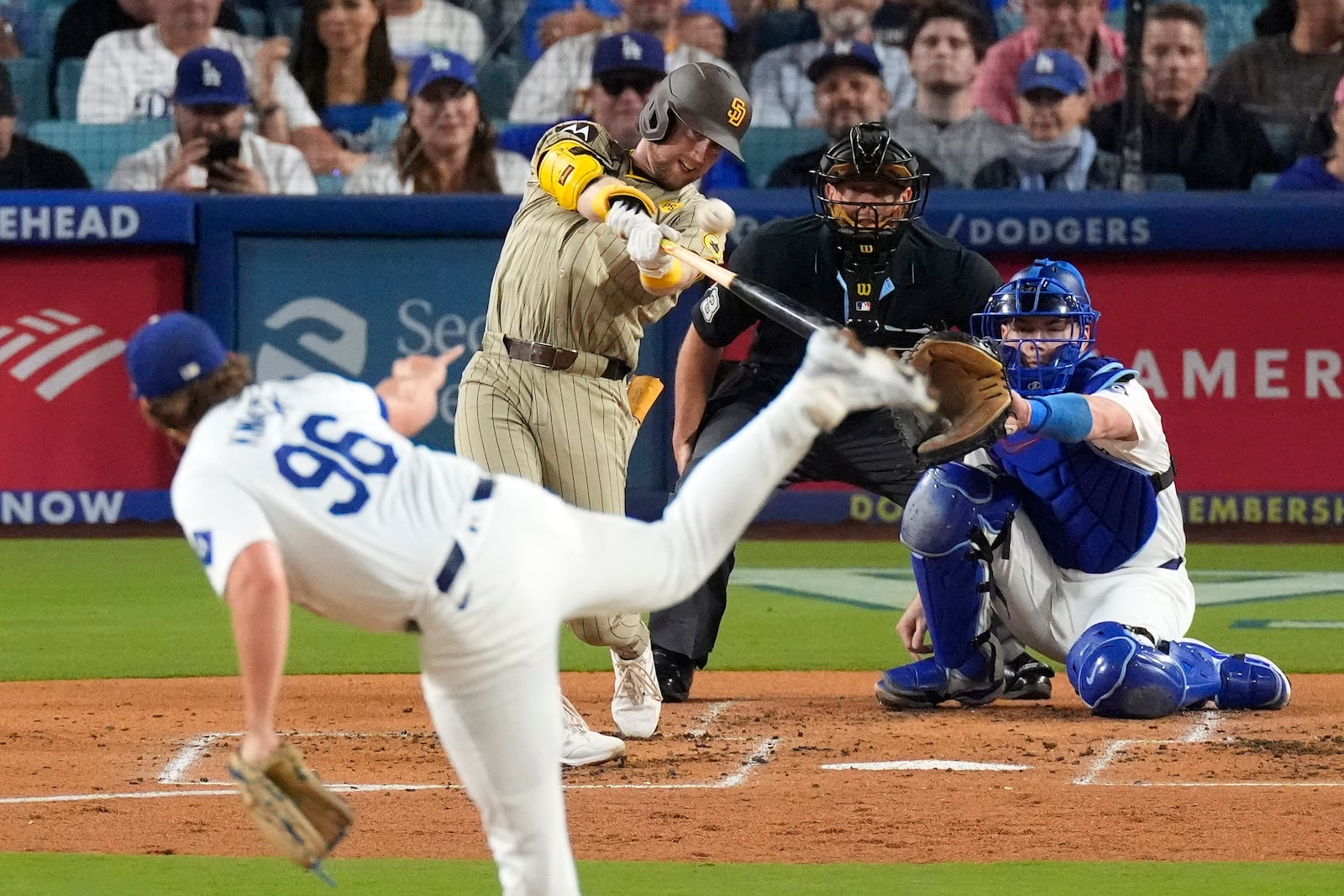 San Diego Padres' Jake Cronenworth, second from left, hits a two-run home run as Los Angeles Dodgers starting pitcher Landon Knack, left, washes along with catcher Will Smith, right, and home plate umpire Tripp Gibson during the second inning of a baseball game, Tuesday, Sept. 24, 2024, in Los Angeles. (AP Photo/Mark J. Terrill)