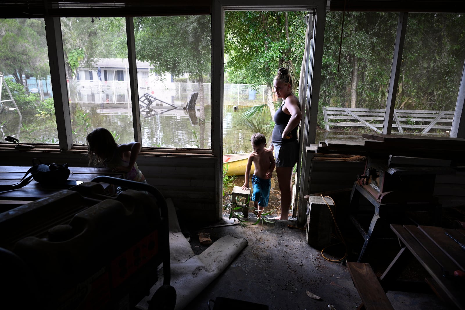 Hailey Morgan, right, surveys the damage to their flooded home after returning with her children, Aria Skye Hall, 7, left, and Kyle Ross, 7, in the aftermath of Hurricane Helene, Friday, Sept. 27, 2024, in Crystal River, Fla. Morgan stayed with her grandmother and her children in Hernando, Fla., as the storm made landfall. (AP Photo/Phelan M. Ebenhack)