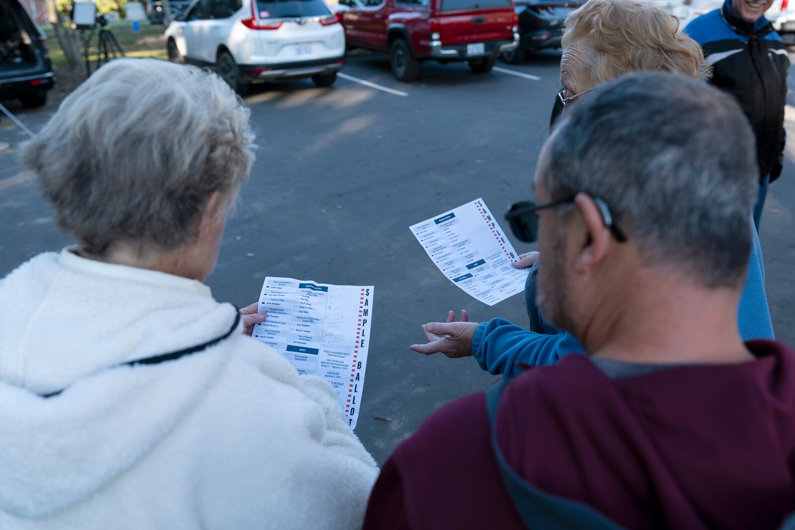 Voters discuss sample ballots while waiting in line to cast their early in-person vote, Thursday, Oct. 17, 2024, in Asheville, N.C. (AP Photo/Stephanie Scarbrough)