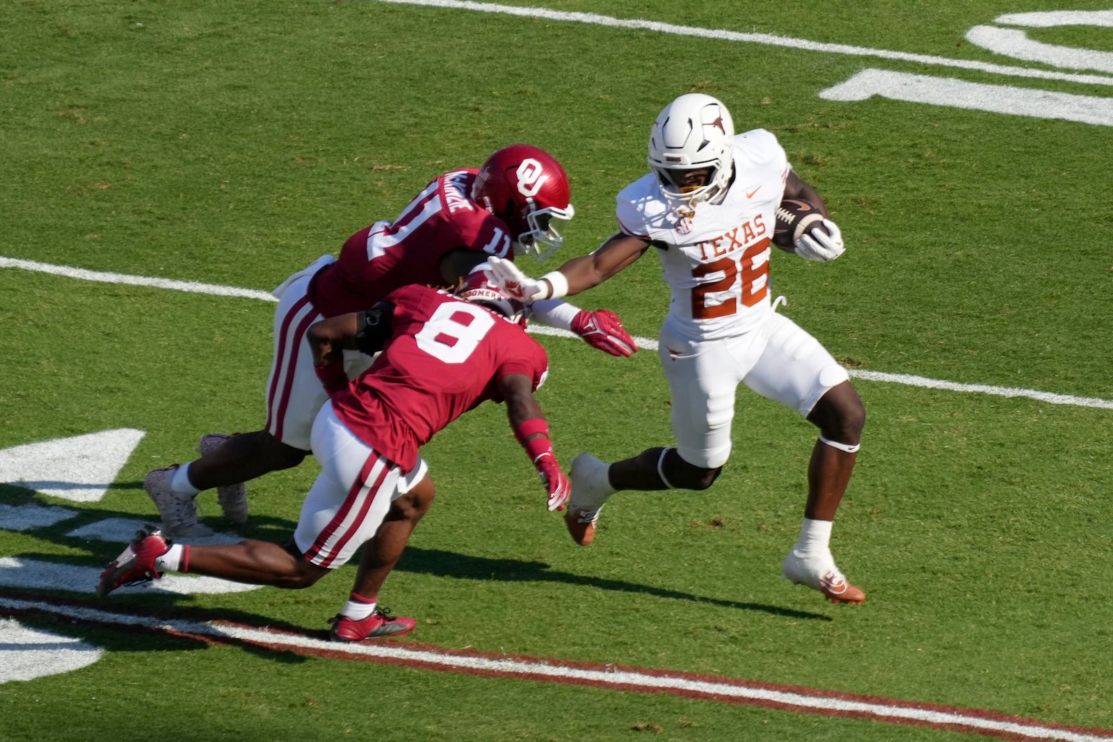 Texas running back Quintrevion Wisner (26) runs the ball as Oklahoma defensive back Makari Vickers (8) and linebacker Kobie McKinzie (11) attempt to make the stop in the first half of an NCAA college football game in Dallas, Saturday, Oct. 12, 2024. (AP Photo/Jeffrey McWhorter)