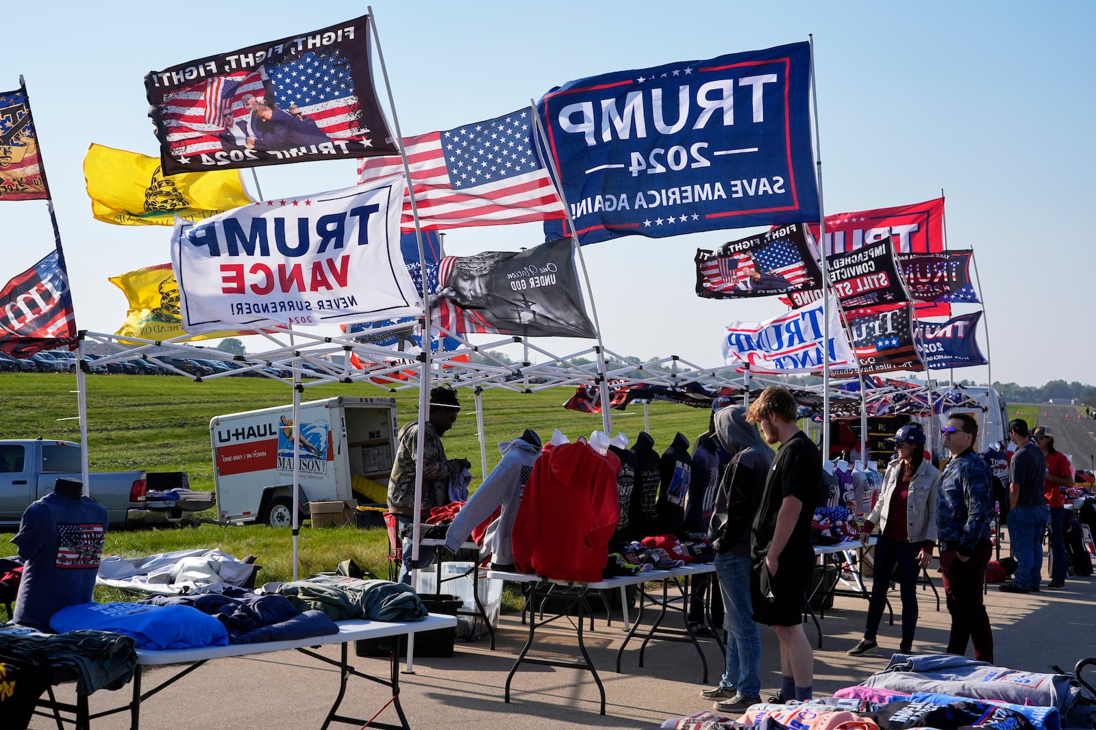 Supporters look at merchandise before Republican presidential nominee former President Donald Trump speaks at a campaign stop at the Dodge County Airport Sunday, Oct. 6, 2024, in Juneau, Wis. (AP Photo/Morry Gash)