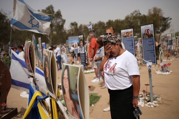 People stand still to observe two minutes of silence as air raid sirens sound marking the Israel's annual Memorial Day at the site of Oct. 7, 2023 attack by Hamas militants at the Nova music festival near Kibbutz Reim, southern Israel, Wednesday, April 30, 2025. (AP Photo/Ohad Zwigenberg)
