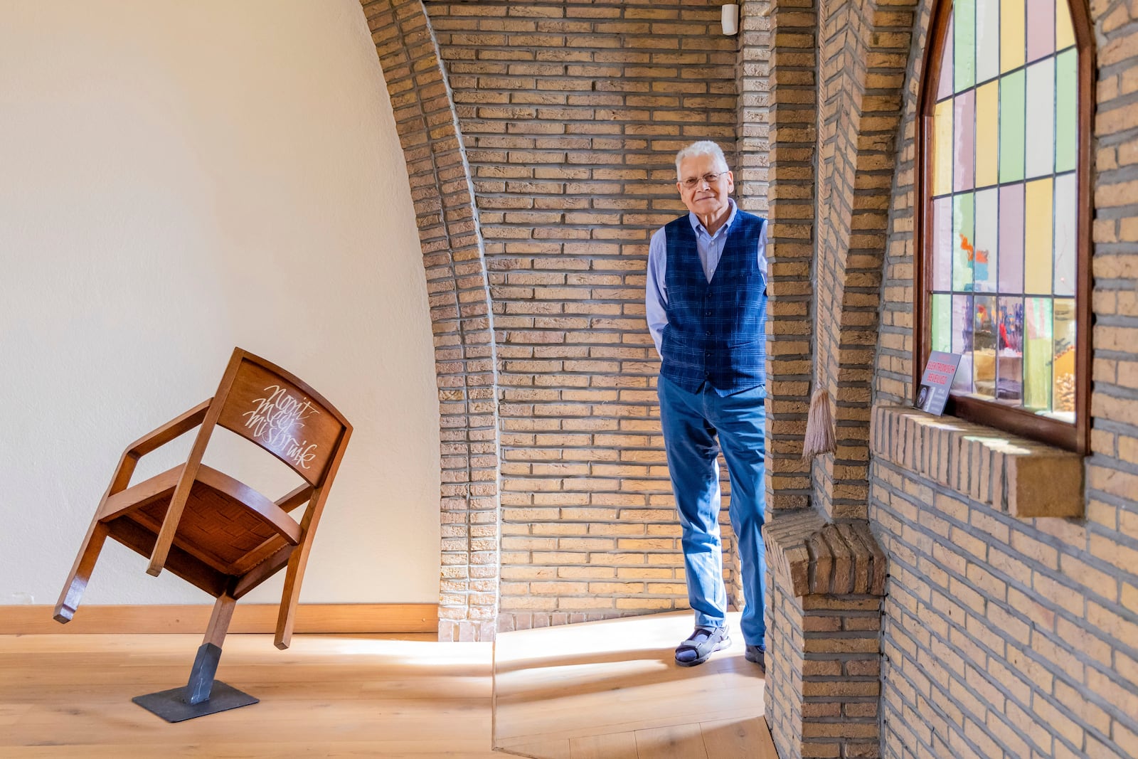 Rik Deville, a retired priest, poses next to a church chair with a message written in Dutch saying "No More Abuse" at the Don Bosco church in Buizingen, Belgium, Sunday, Sept. 8, 2024. (AP Photo/Geert Vanden Wijngaert)