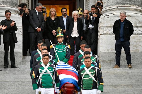 Uruguay's President Yamandu Orsi, back left, his wife Laura Alonsoperez, second from left, and Lucia Topolansky, the widow of late former President Jose Mujica, watch the honor guard carry his casket after funeral ceremonies at the Legislative Palace in Montevideo, Uruguay, Thursday, May 15, 2025. (AP Photo/Santiago Mazzarovich)