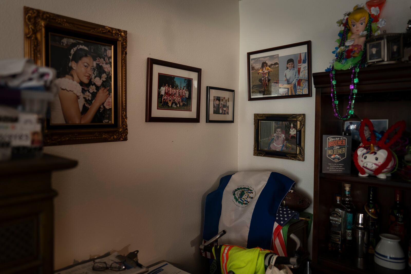 A wall in Marina Maalouf's apartment is adorned with family photos as an El Salvadoran flag is draped over an American flag in Los Angeles, Tuesday, Oct. 1, 2024. (AP Photo/Jae C. Hong)