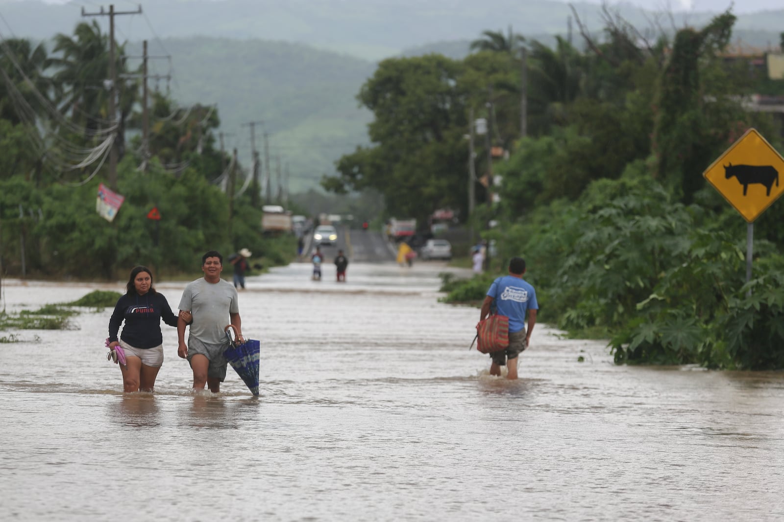 Residents wade through a street flooded by the passing of Hurricane John, in Acapulco, Mexico, Friday, Sept. 27, 2024. (AP Photo/Bernardino Hernandez)