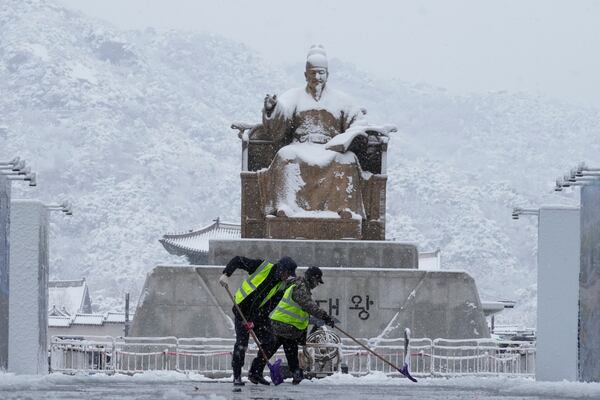 Workers clean snow in front of the statue of King Sejong at Gwanghwamun Square in Seoul, South Korea, Wednesday, Nov. 27, 2024. (AP Photo/Ahn Young-joon)