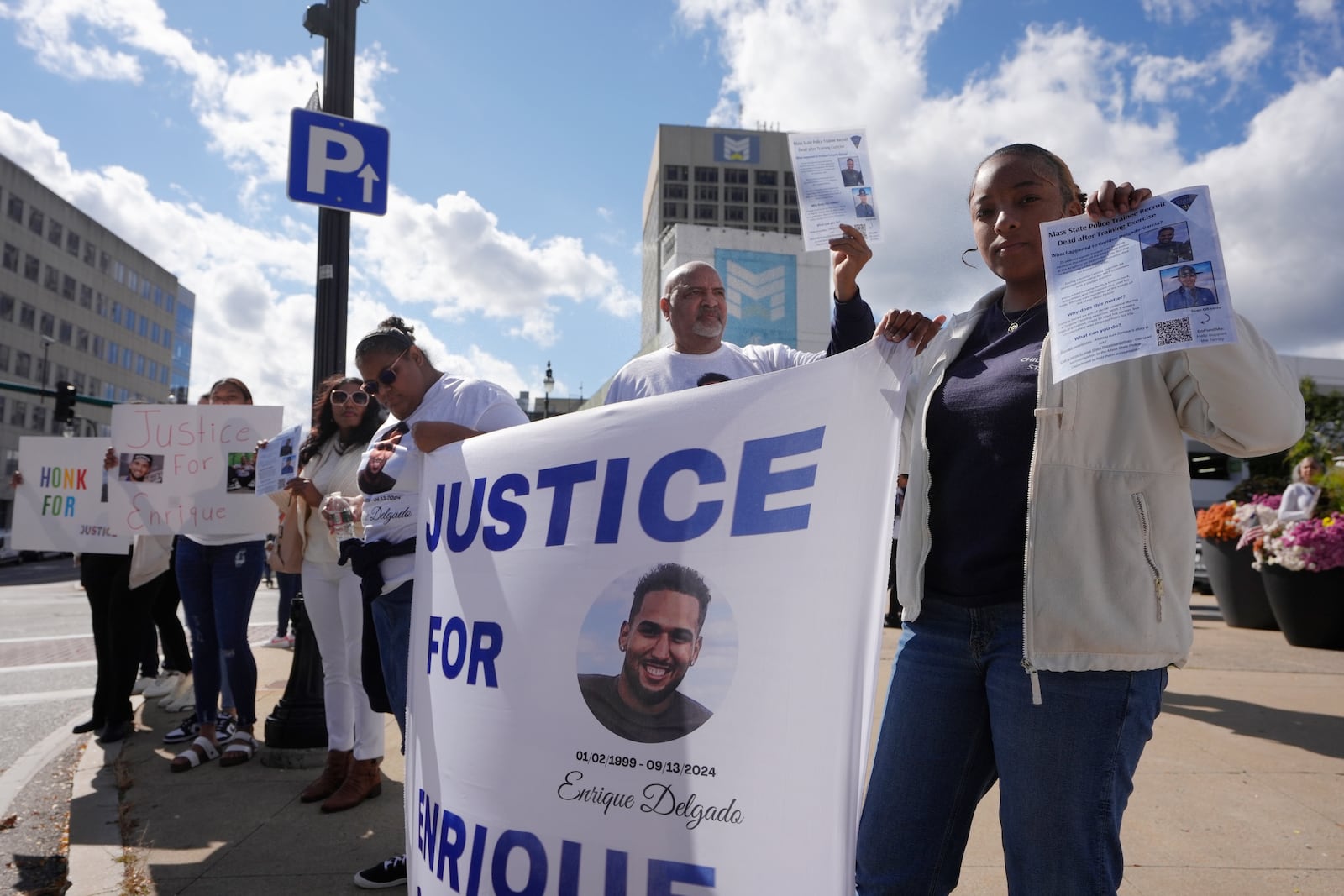 People display signs with with a likeness of Massachusetts State Police recruit Enrique Delgado-Garcia, who died following a State Police Academy training exercise, at a protest outside the State Police Academy graduation ceremony, Wednesday, Oct. 9, 2024, at the DCU Center, in Worcester, Mass. (AP Photo/Steven Senne)