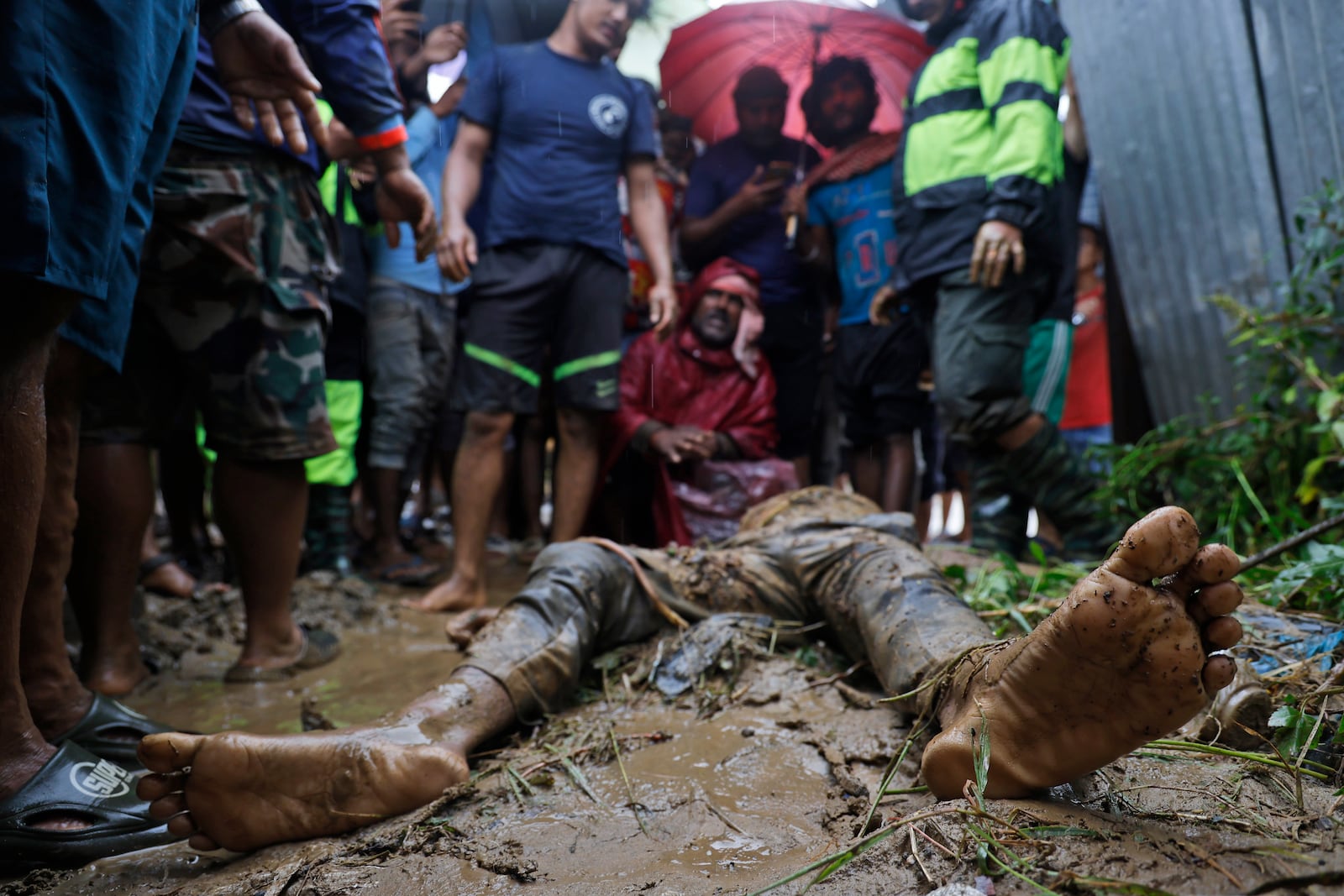 EDS NOTE: GRAPHIC CONTENT - People, including relatives, stand by the body of Nandu Sah, 34, a scrap dealer, who died after the shed he was sleeping under was flooded due to heavy rains, on the outskirts of Kathmandu, Nepal, Saturday, Sept. 28, 2024. (AP Photo/Gopen Rai)