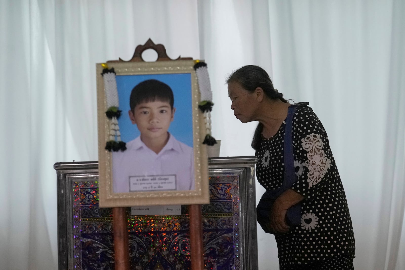 A relative looks at the coffin of a victim of school bus fire at Wat Khao Phraya Sangkharam School Lan Sak, Uthai Thani province, Thailand, Thursday, Oct. 3, 2024. (AP Photo/Sakchai Lalit)