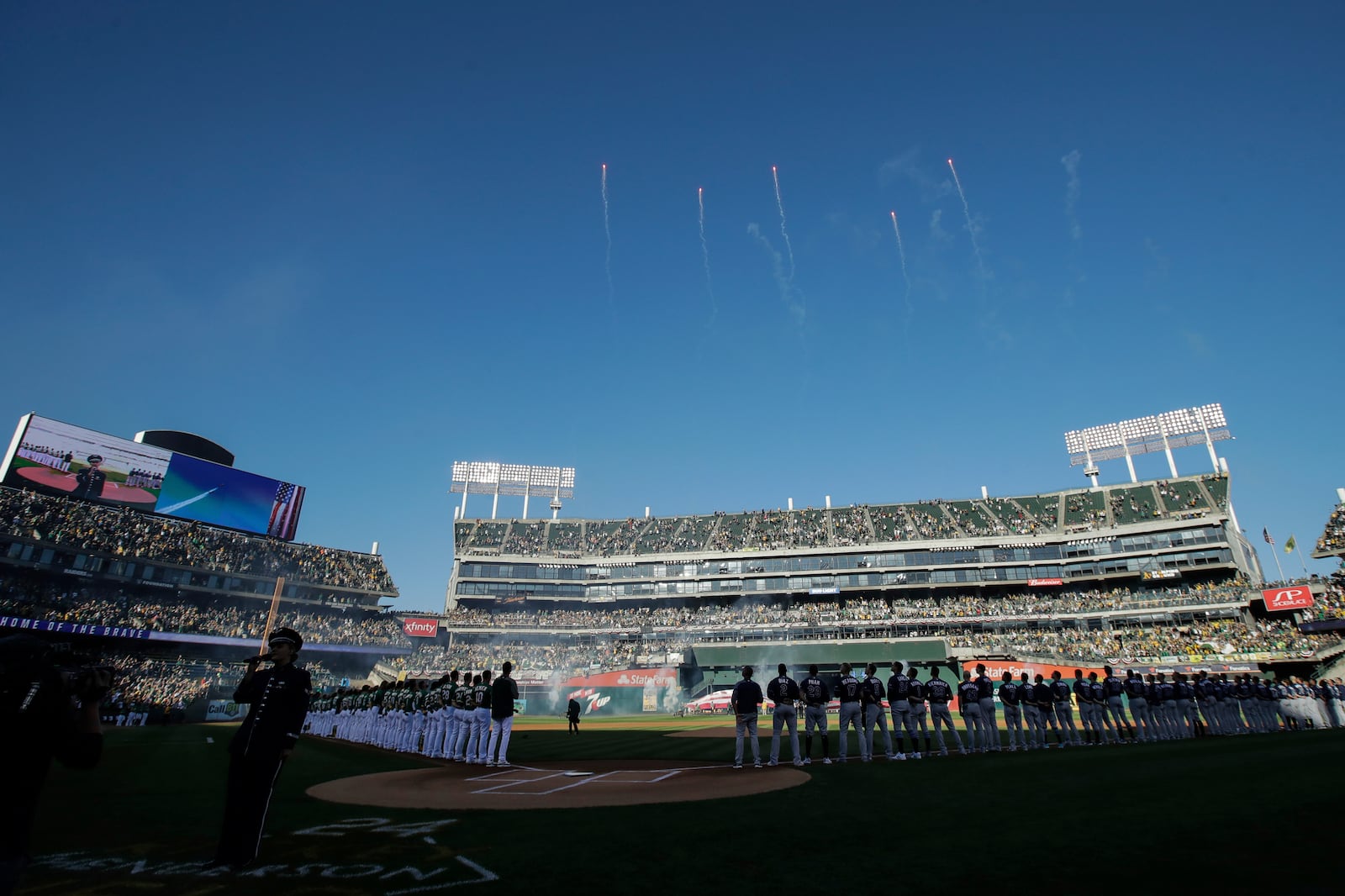 FILE - Fans at Oakland Coliseum listen as the national anthem is performed before an American League wild-card baseball game between the Oakland Athletics and the Tampa Bay Rays in Oakland, Calif., Wednesday, Oct. 2, 2019. (AP Photo/Jeff Chiu, File)