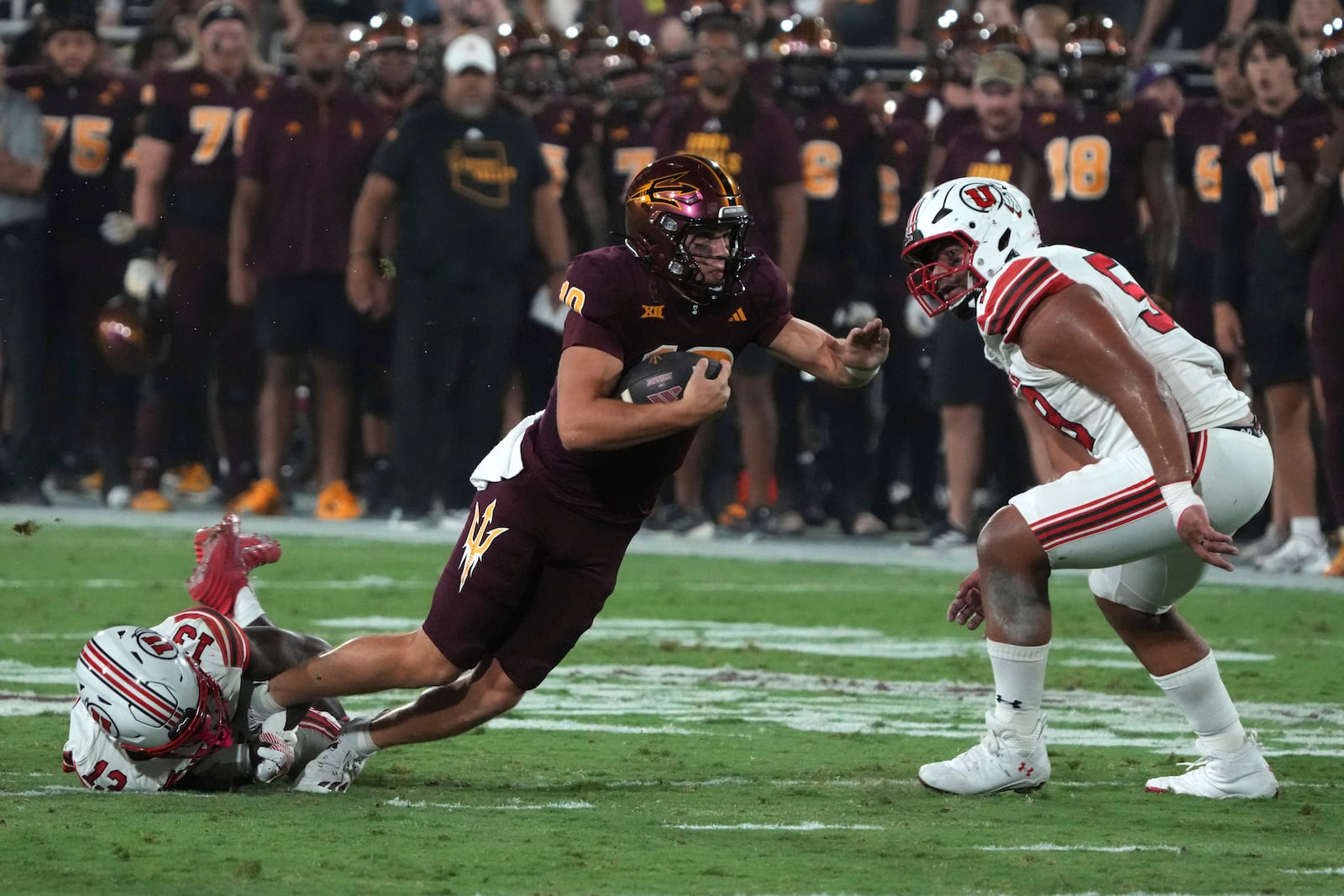 Arizona State quarterback Sam Leavitt dives between Utah safety Rabbit Evans (13) and defensive tackle Junior Tafuna in the first half during an NCAA college football game, Friday, Oct. 11, 2024, in Tempe, Ariz. (AP Photo/Rick Scuteri)