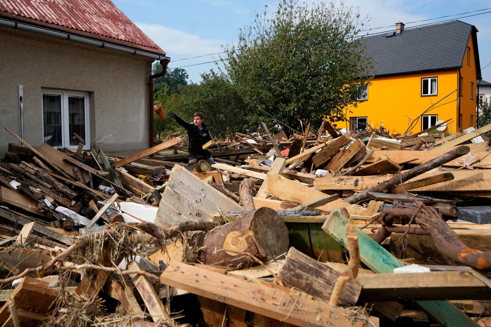 A young man throws a piece of wood as residents return to clean up after recent floods in Mikulovice, Czech Republic, Thursday, Sept. 19, 2024. (AP Photo/Petr David Josek)