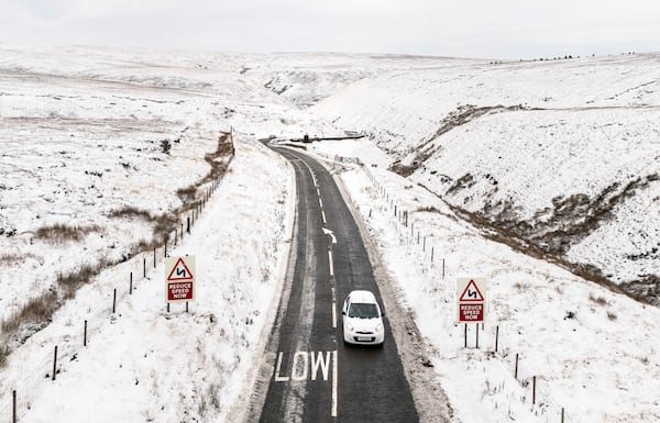 A car moves on the A57 Snake Pass between snowy fields near Glossop, England, Tuesday Nov. 19, 2024. (Danny Lawson/PA via AP)