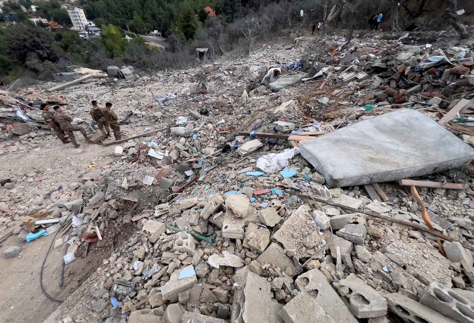 Lebanese army soldiers stand on the rubble of a destroyed building at the site of Monday's Israeli airstrike in the village of Aito, north Lebanon, Tuesday, Oct. 15, 2024. (AP Photo/Hussein Malla)