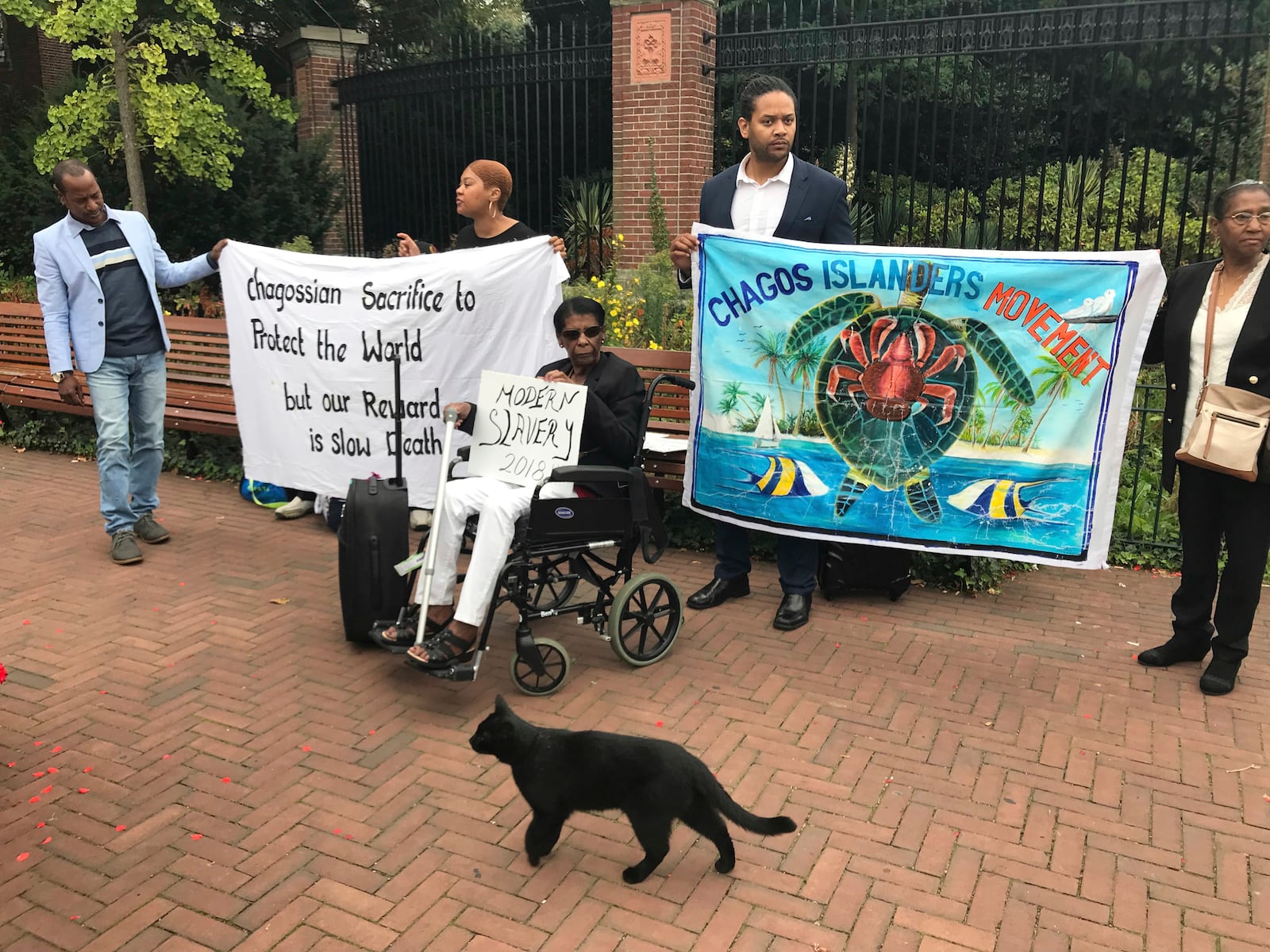 FILE - Protesters hold banners outside the World Court in The Hague, Netherlands, Monday, Sept. 3, 2018, where judges listen to arguments in a case on whether Britain illegally maintains sovereignty over the Chagos Islands. (AP Photo/Mike Corder, File)