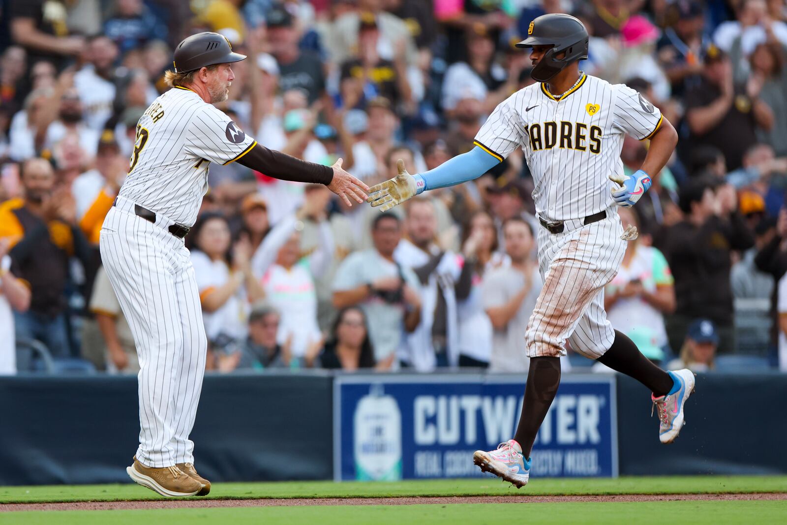 San Diego Padres' Xander Bogaerts, right, celebrates a two-run home run with third base coach Tim Leiper during the second inning of a baseball game against the Chicago White Sox, Saturday, Sept. 21, 2024, in San Diego. (AP Photo/Ryan Sun)