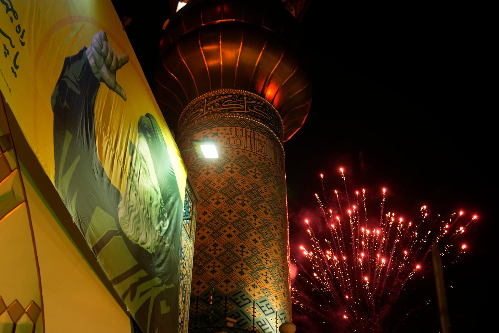 Fireworks explode next a portrait of slain Hezbollah leader Hassan Nasrallah and a minaret of a mosque in an anti-Israeli gathering celebrating Iran's missile strike against Israel, at Felestin (Palestine) Sq. in Tehran, Iran, Tuesday, Oct. 1, 2024. (AP Photo/Vahid Salemi)