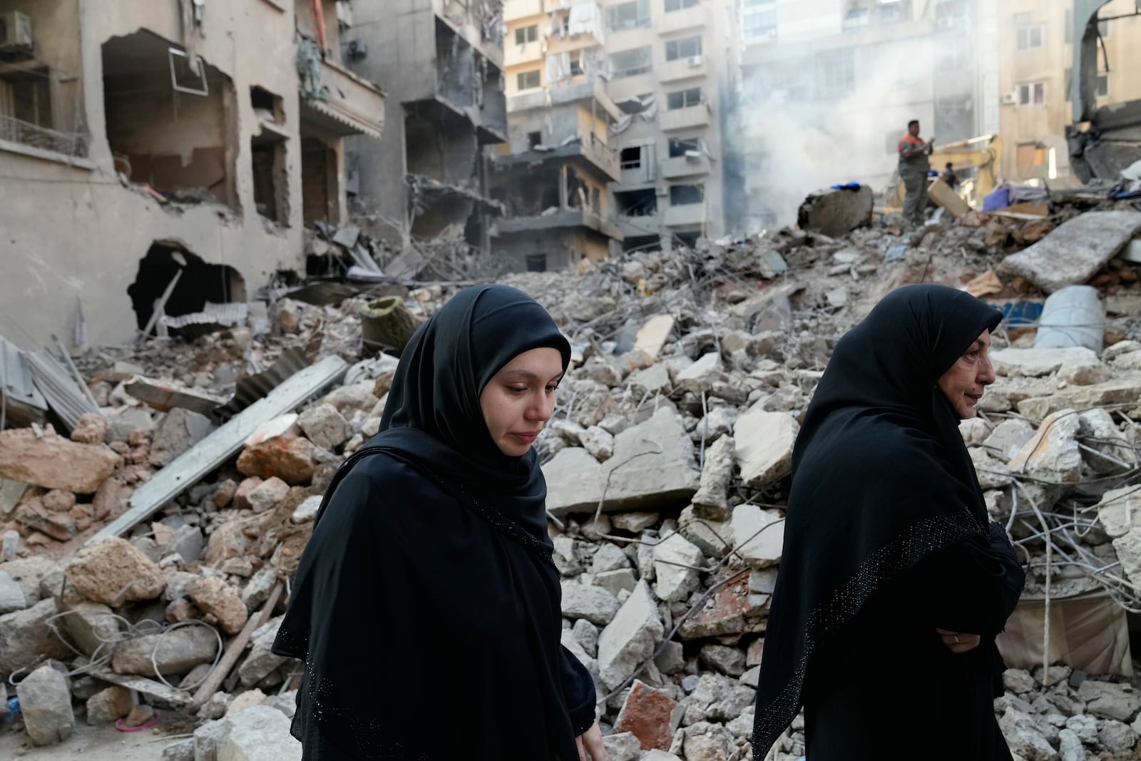 Lebanese women pass the destroyed buildings hit by an Israeli airstrike, in Beirut, Lebanon, Friday, Oct. 11, 2024. (AP Photo/Hussein Malla)