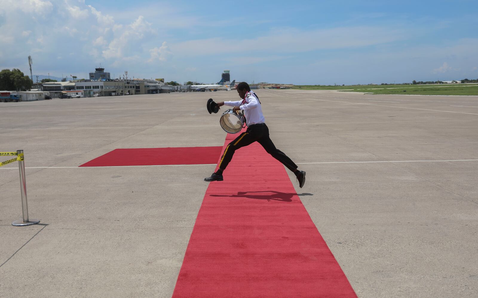 A member of the Police Music Band jumps over the welcome mat before the arrival of Kenya's President William Ruto at the Toussaint Louverture International Airport in Port-au-Prince, Haiti, Saturday, Sept. 21, 2024. (AP Photo/Odelyn Joseph)