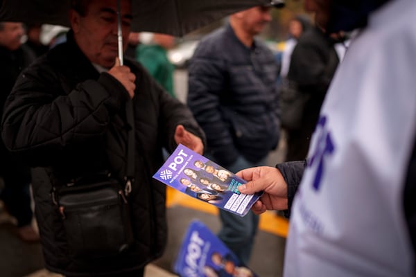 A man distributes leaflets of the Young People's Party or POT, which has backed Calin Georgescu, an independent candidate who won the first round of presidential elections, in Bucharest, Romania, Friday, Nov. 29, 2024. (AP Photo/Andreea Alexandru)