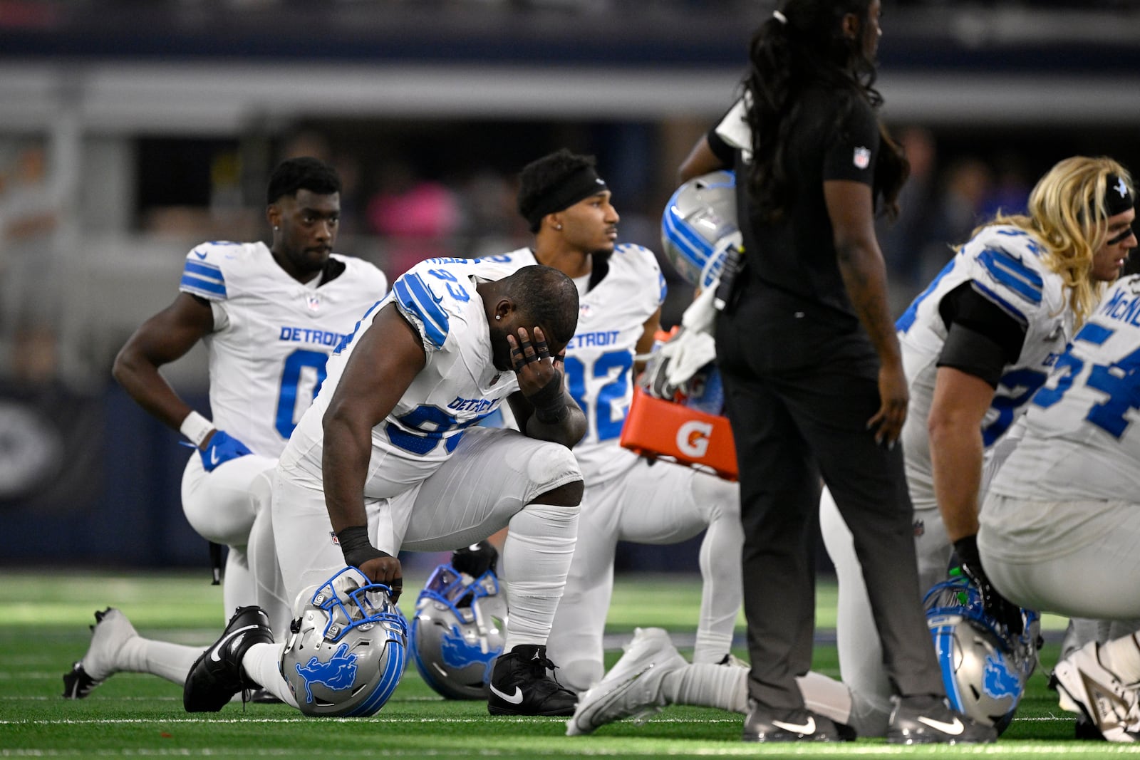 Detroit Lions players kneel on the field as Aidan Hutchinson, not pictured, is attended to by staff afer suffering an unkown injury second half of an NFL football game against the Dallas Cowboys in Arlington, Texas, Sunday, Oct. 13, 2024. (AP Photo/Jerome Miron)