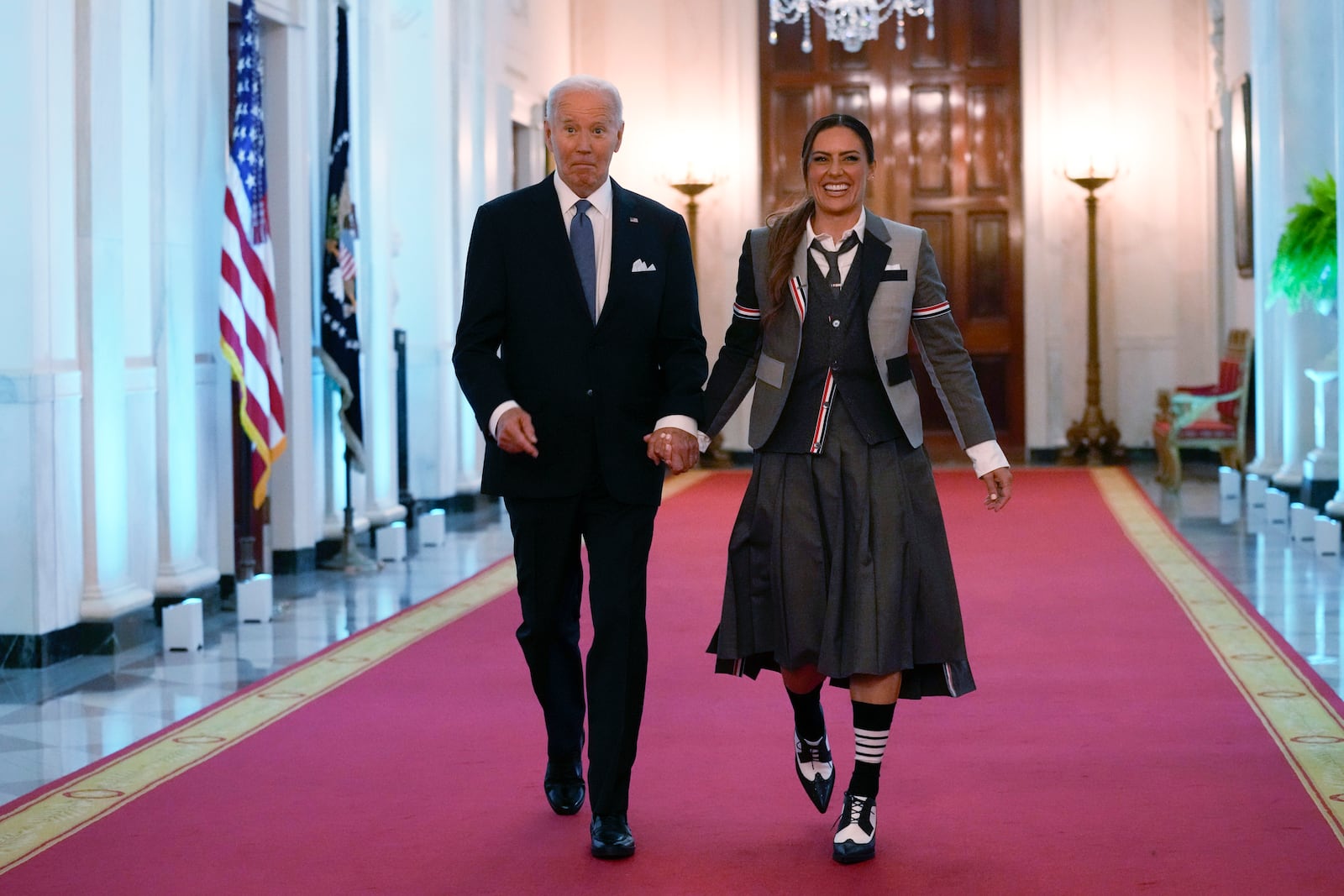 President Joe Biden walks with Ali Krieger, a member of the 2023 NWSL championship NJ/NY Gotham FC team, as they arrive for an event in the East Room of the White House in Washington, Monday, Sept. 23, 2024, to welcome the team and celebrate their championship. (AP Photo/Susan Walsh)