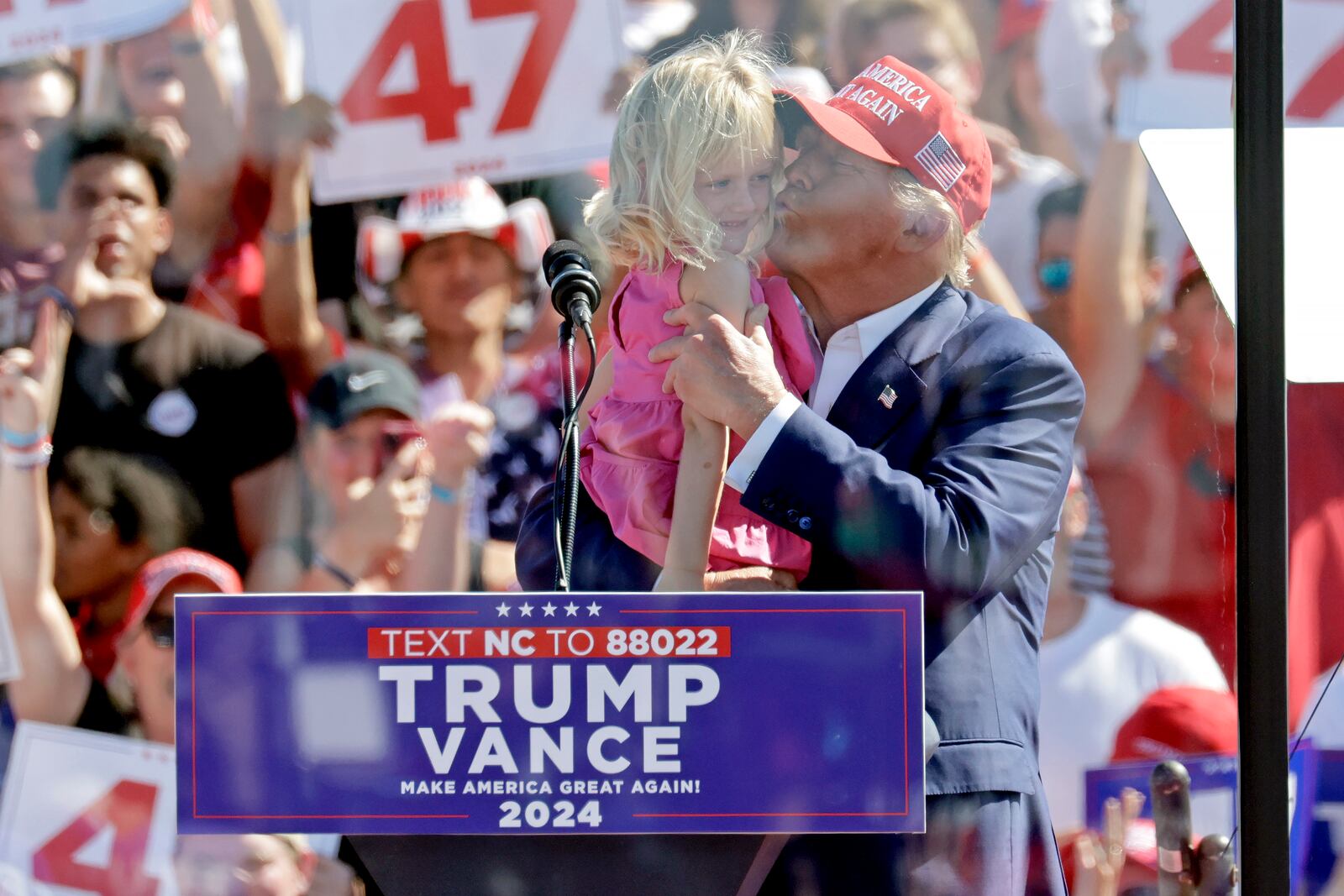 Republican presidential nominee former President Donald Trump kisses his granddaughter Carolina Trump as he speaks at a campaign event at Wilmington International Airport in Wilmington, N.C., Saturday, Sept. 21, 2024. (AP Photo/Chris Seward)