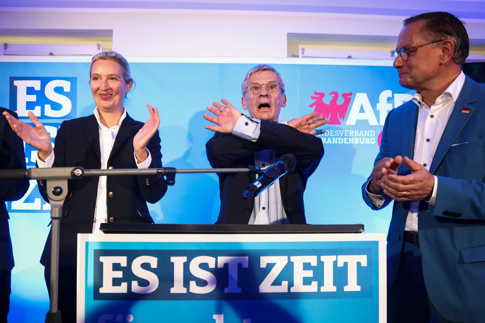 Right-wing Alternative for Germany (AfD) Brandenburg top candidate Hans-Christoph Berndt, center, gestures next to AfD party co-leaders Alice Weidel, left, and Tino Chrupalla, right, as they react after first exit polls of the Brandenburg state election in Potsdam, Germany, Sunday, Sept. 22, 2024. (Liesa Johannssen/Pool Photo via AP)