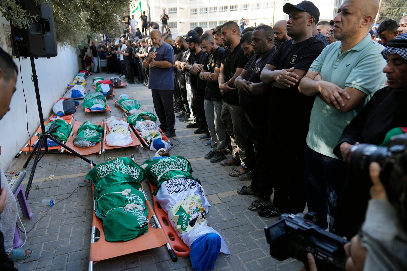 Mourners pray by the bodies of 18 Palestinians who were killed in an Israeli airstrike during their funeral in Tulkarem, Friday, Oct. 4, 2024. (AP Photo/Nasser Nasser)