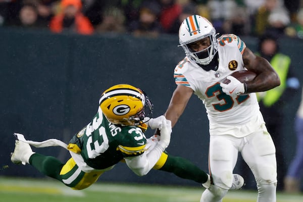 Miami Dolphins running back Raheem Mostert (31) tries to break a tackle by Green Bay Packers safety Evan Williams (33) during the second half of an NFL football game Thursday, Nov. 28, 2024, in Green Bay, Wis. (AP Photo/Matt Ludtke)