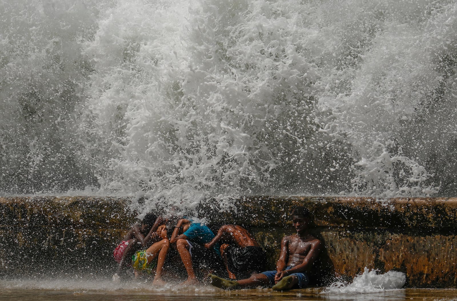 Youths duck behind the Malecon seawall as they play in the surf brought by Hurricane Milton passing through the Gulf of Mexico, in Havana, Cuba, Wednesday, Oct. 9, 2024. (AP Photo/Ramon Espinosa)