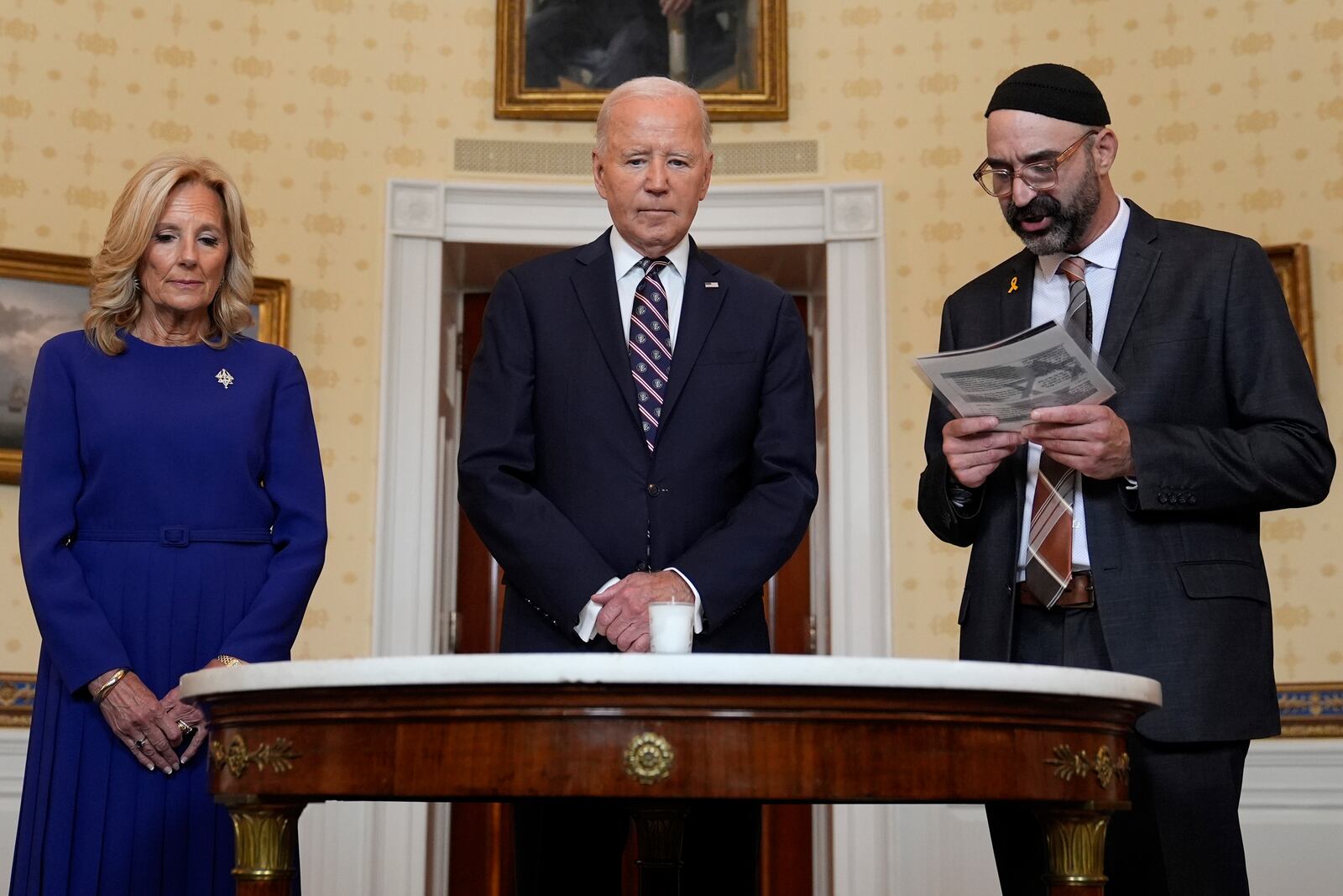 President Joe Biden, center, standing with first lady Jill Biden, left, and Rabbi Aaron Alexander of the Adas Israel Congregation, participates in a memorial candle-lighting in the Blue Room of the White House in Washington, Monday, Oct. 7, 2024, to mark the one-year anniversary of the Hamas attack on Israel that left about 1,200 people dead. (AP Photo/Susan Walsh)