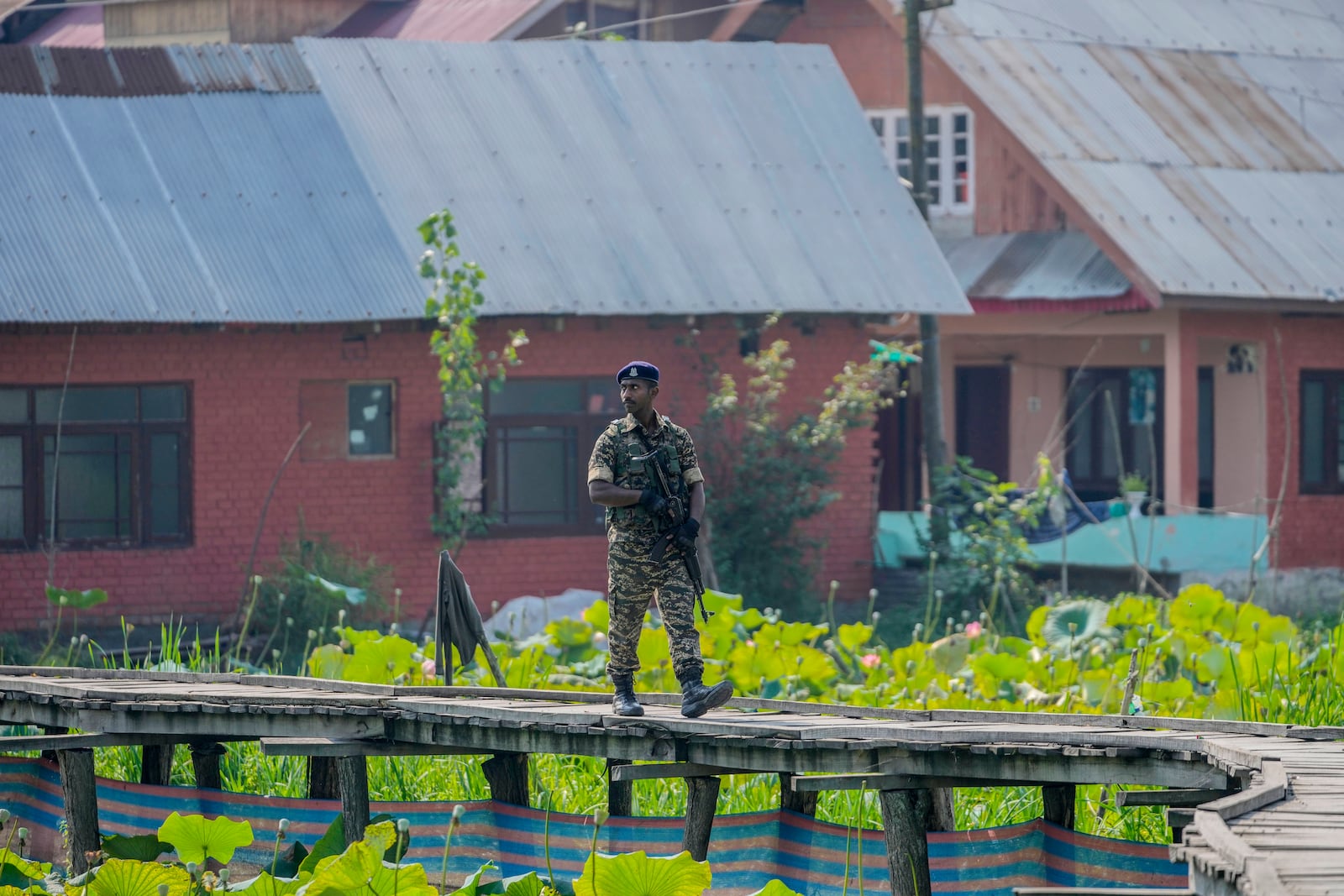 An Indian soldier on patrol walks on a wooden bridge inside the interior of Dal Lake during the second phase of the assembly election in Srinagar, Indian controlled Kashmir, Wednesday, Sept. 25, 2024 (AP Photo/Mukhtar Khan)