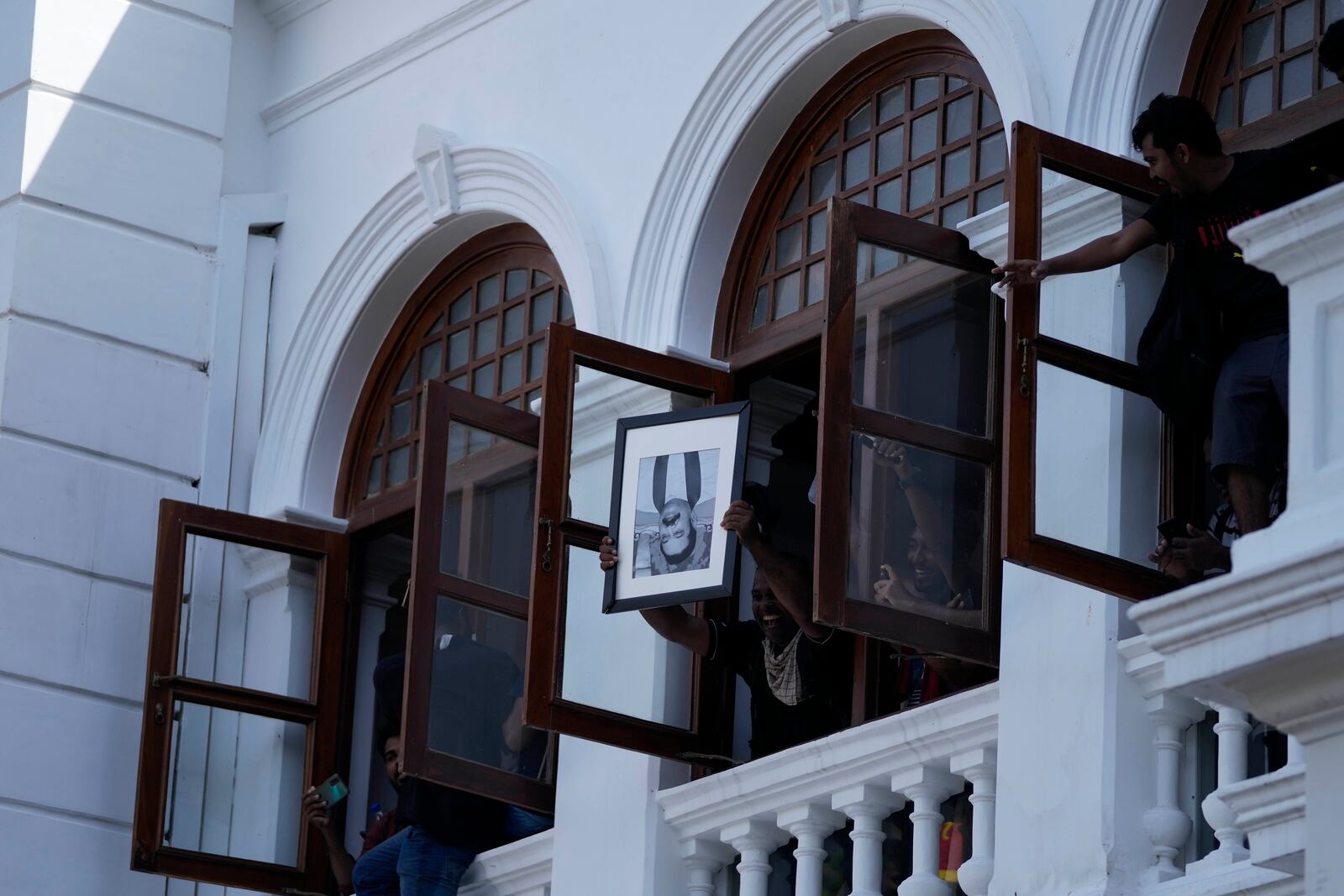 FILE - A protester holds a portrait of former Sri Lankan Prime Minister Mahinda Rajapaksa upside down after storming the Prime Minister Ranil Wickremesinghe's office demanding he resign after president Gotabaya Rajapaksa fled the country amid economic crisis, in Colombo, Sri Lanka, on July 13, 2022. (AP Photo/Eranga Jayawardena, File)