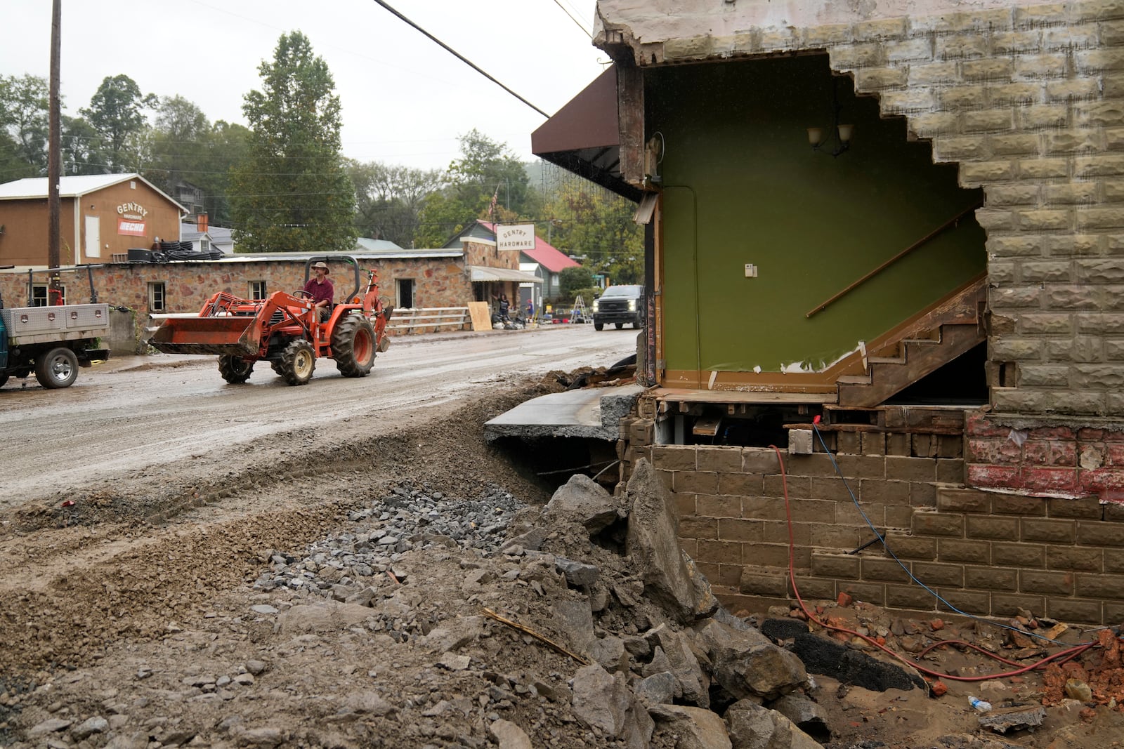 A person driving a front in loader passes a heavily one of several heavily damaged buildings along Bridge Street as clean up begins in the aftermath of Hurricane Helene Tuesday, Oct. 1, 2024, in Hot Springs, N.C. (AP Photo/Jeff Roberson)