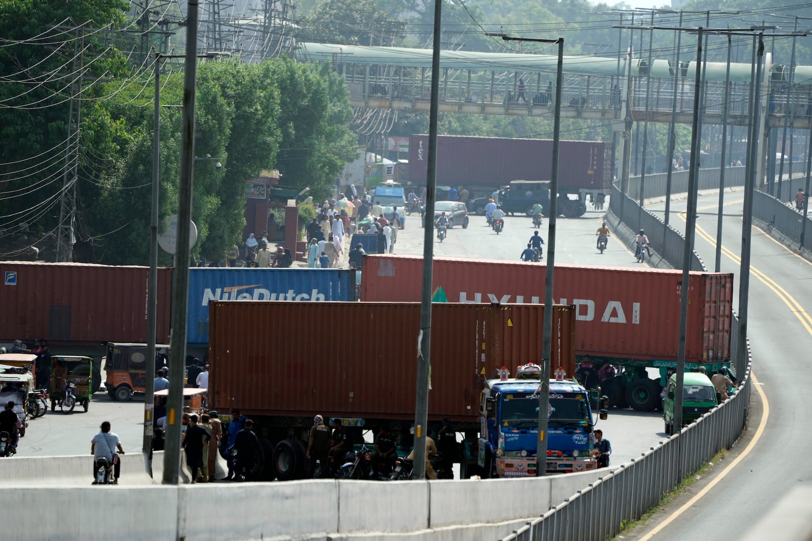 Shipping containers set up by authorities block a road, preventing the supporters of imprisoned former Prime Minister Imran Khan from holding a rally to demand his release in Lahore, Pakistan, Saturday, Oct. 5, 2024. (AP Photo/K.M. Chaudary)