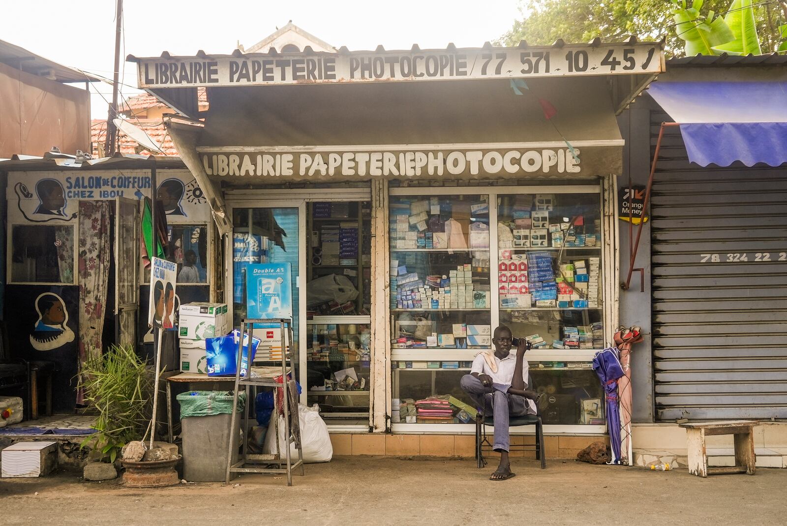 A man sits outside a stationary store with French signs in Dakar, Senegal, Thursday, Oct. 3, 2024. (AP Photo/Annie Risemberg)