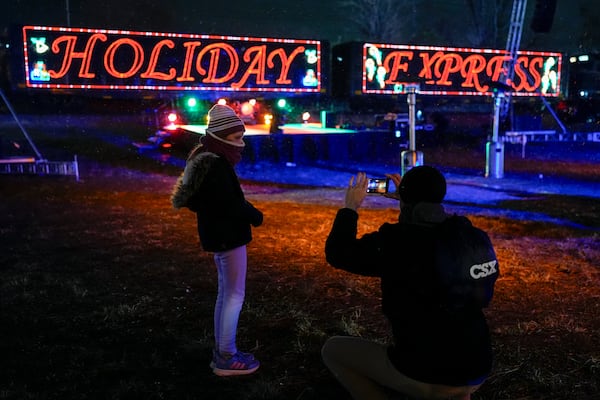 Eden Jordan, left, poses for her father Tim Jordan, right, in front of the CSX Holiday Express, Thursday, Nov. 21, 2024, in Erwin, Tenn. The railway company held a celebration and concert for the town affected by Hurricane Helene. (AP Photo/George Walker IV)