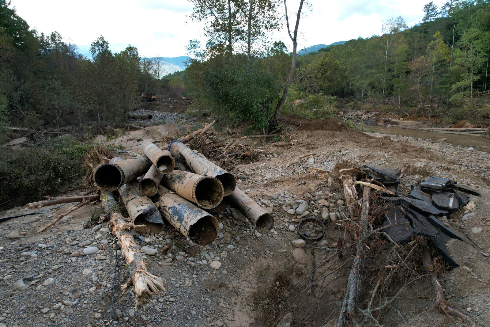 The remnants of a waterline serving Asheville, N.C., is piled up downstream from North Fork Reservoir, a main source of water for the city, Wednesday, Oct. 2, 2024, after the line was destroyed during Hurricane Helene in Black Mountain, N.C. (AP Photo/Jeff Roberson)