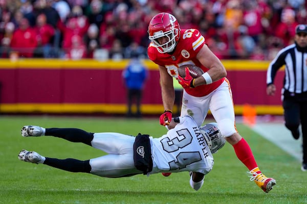 Kansas City Chiefs tight end Travis Kelce (87) is tackled by Las Vegas Raiders safety Thomas Harper (34) during the first half of an NFL football game in Kansas City, Mo., Friday, Nov. 29, 2024. (AP Photo/Ed Zurga)