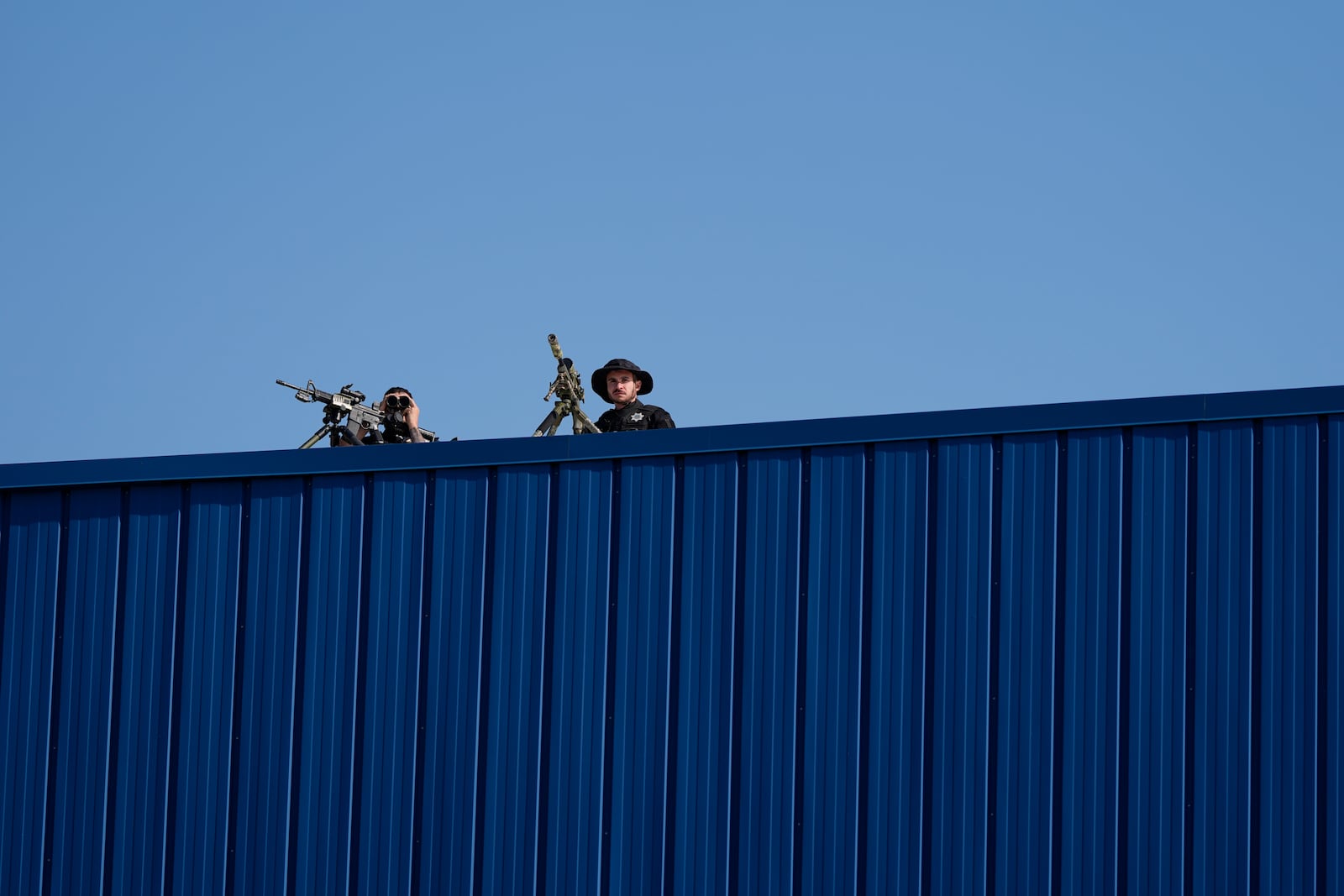 Law enforcement snipers sit on a roof before Republican presidential nominee former President Donald Trump arrives to speak at a campaign rally at Dodge County Airport, Sunday, Oct. 6, 2024, in Juneau, Wis. (AP Photo/Julia Demaree Nikhinson)