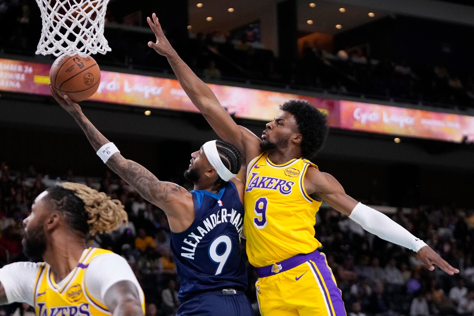 Minnesota Timberwolves guard Nickeil Alexander-Walker, center, shoots as Los Angeles Lakers guard Bronny James, right, defends during the first half of a preseason NBA basketball game, Friday, Oct. 4, 2024, in Palm Desert, Calif. (AP Photo/Mark J. Terrill)