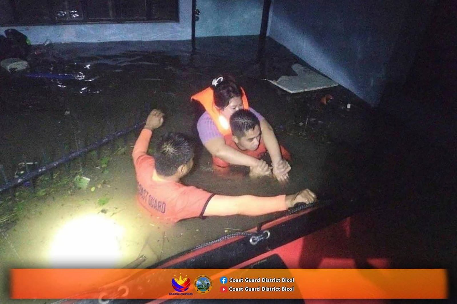 In this photo provided by the Philippine Coast Guard, rescuers carry a resident to safer grounds as they navigate floods caused by Tropical Storm Trami in Guinobatan, Albay province, Philippines Tuesday Oct. 22, 2024. (Philippine Coast Guard via AP)