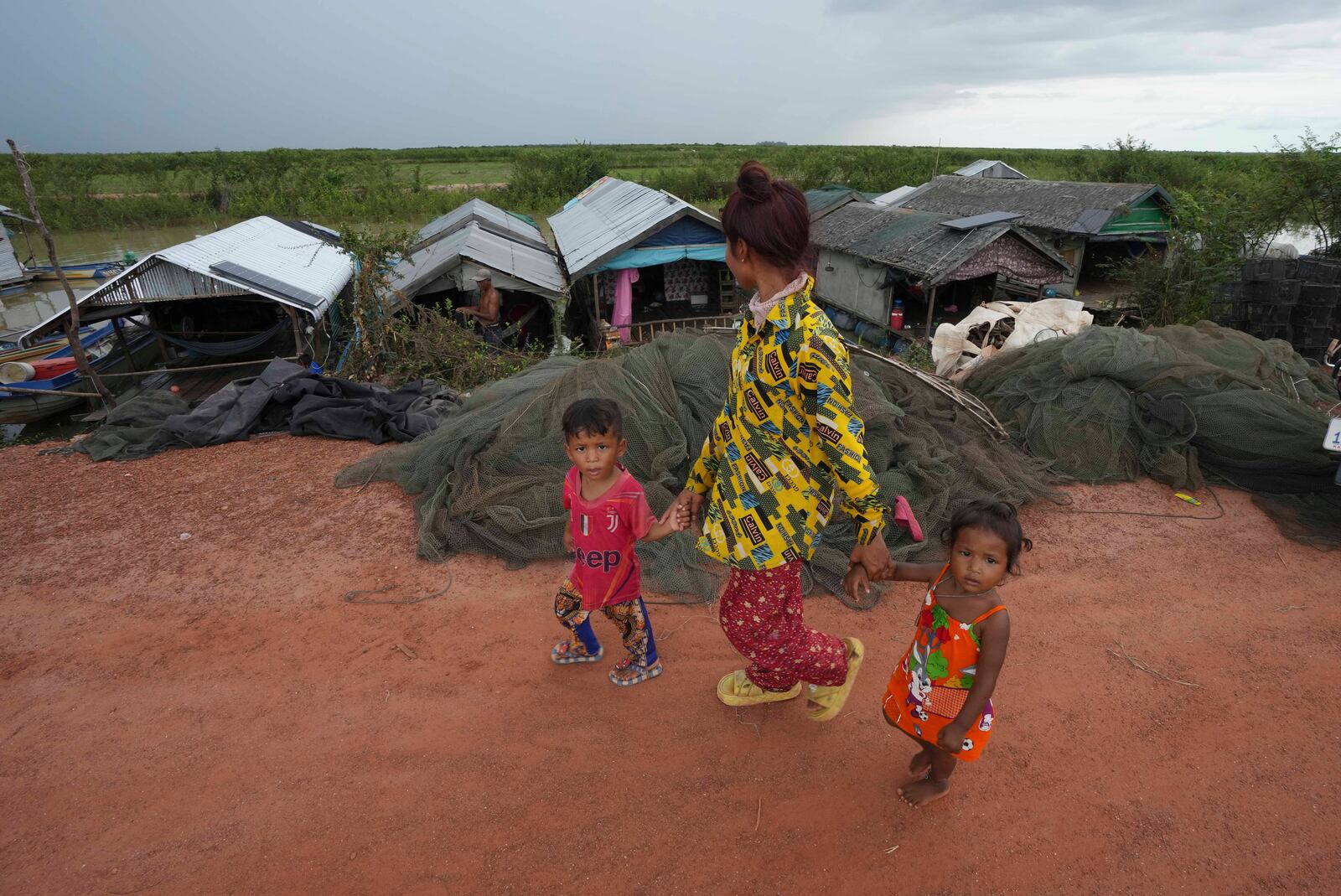 Children walk past a floating village, by the Tonle Sap in Kampong Chhnang province, Cambodia, Thursday, Aug. 1, 2024, (AP Photo/Heng Sinith)