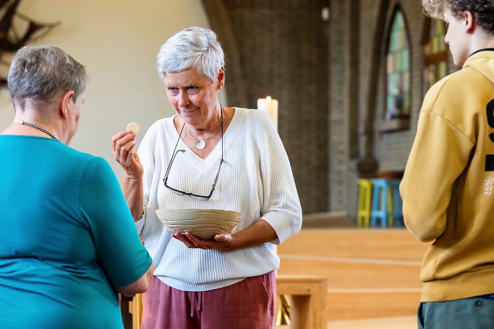 Laywoman Marijke Devaddere, center, hands over a host to a parishioner at the Don Bosco church in Buizingen, Belgium, Sunday, Sept. 8, 2024. (AP Photo/Geert Vanden Wijngaert)