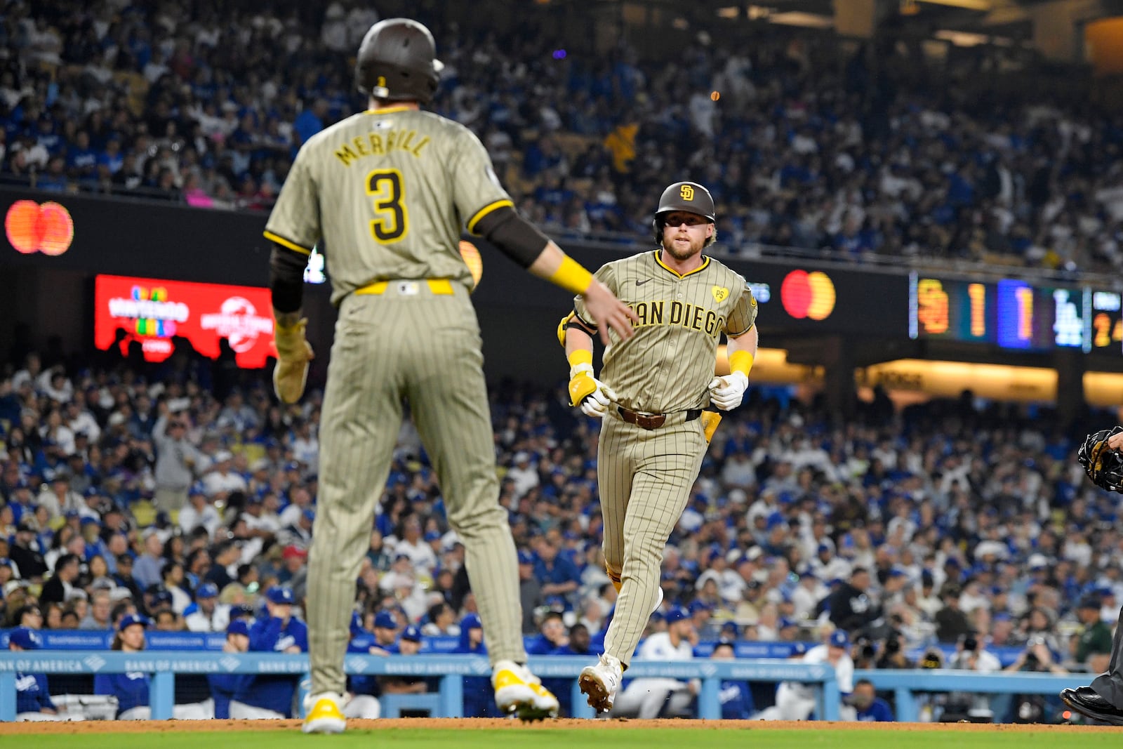 San Diego Padres' Jake Cronenworth, right, scores after hitting a two-run home run as Jackson Merrill waits to congratulate him during the second inning of a baseball game against the Los Angeles Dodgers, Tuesday, Sept. 24, 2024, in Los Angeles. (AP Photo/Mark J. Terrill)