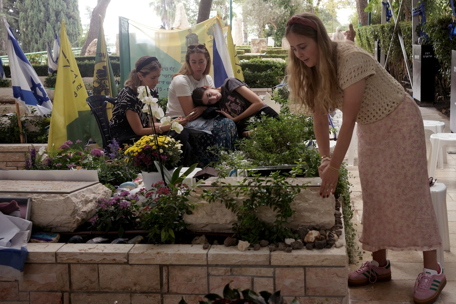 Senai Guedalia tidies the grave of her husband, Sgt. 1st Class Yosef Guedalia, who was killed one year ago at as Israel marks the one-year anniversary of the Hamas attack on Israel, at Mt. Herzl military cemetery in Jerusalem on Monday, Oct. 7, 2024. (AP Photo/Maya Alleruzzo)